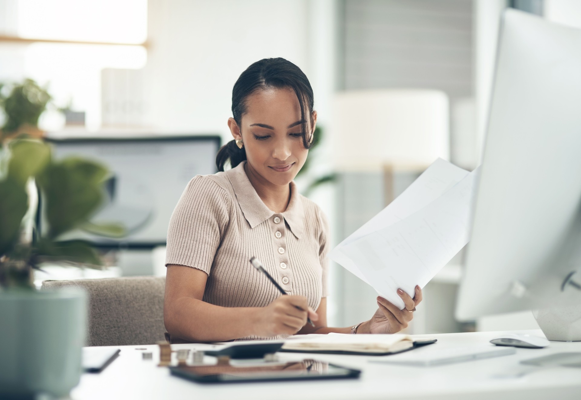 Shot of a young businesswoman calculating finances in an office